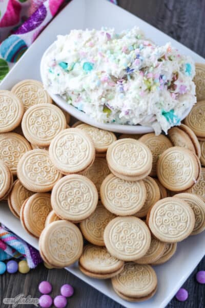 Bowl of Easter funfetti dip on a tray with Golden Oreo cookies