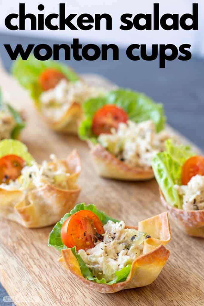 chicken salad wonton cups with lettuce and tomato on a wooden board