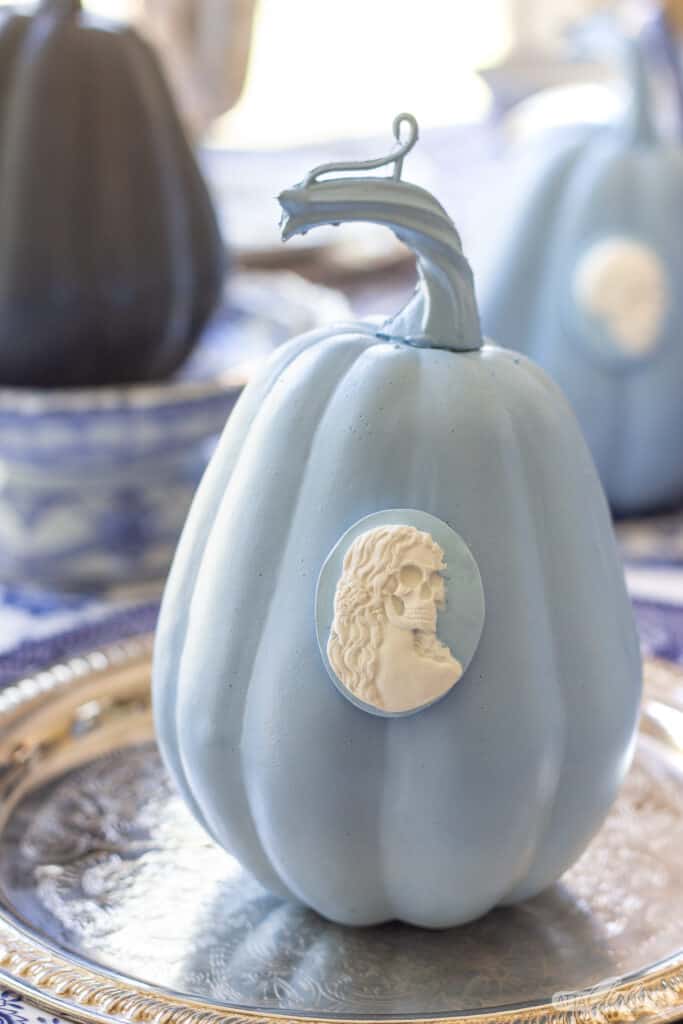 blue and white pumpkin with a skeleton cameo attached to it
