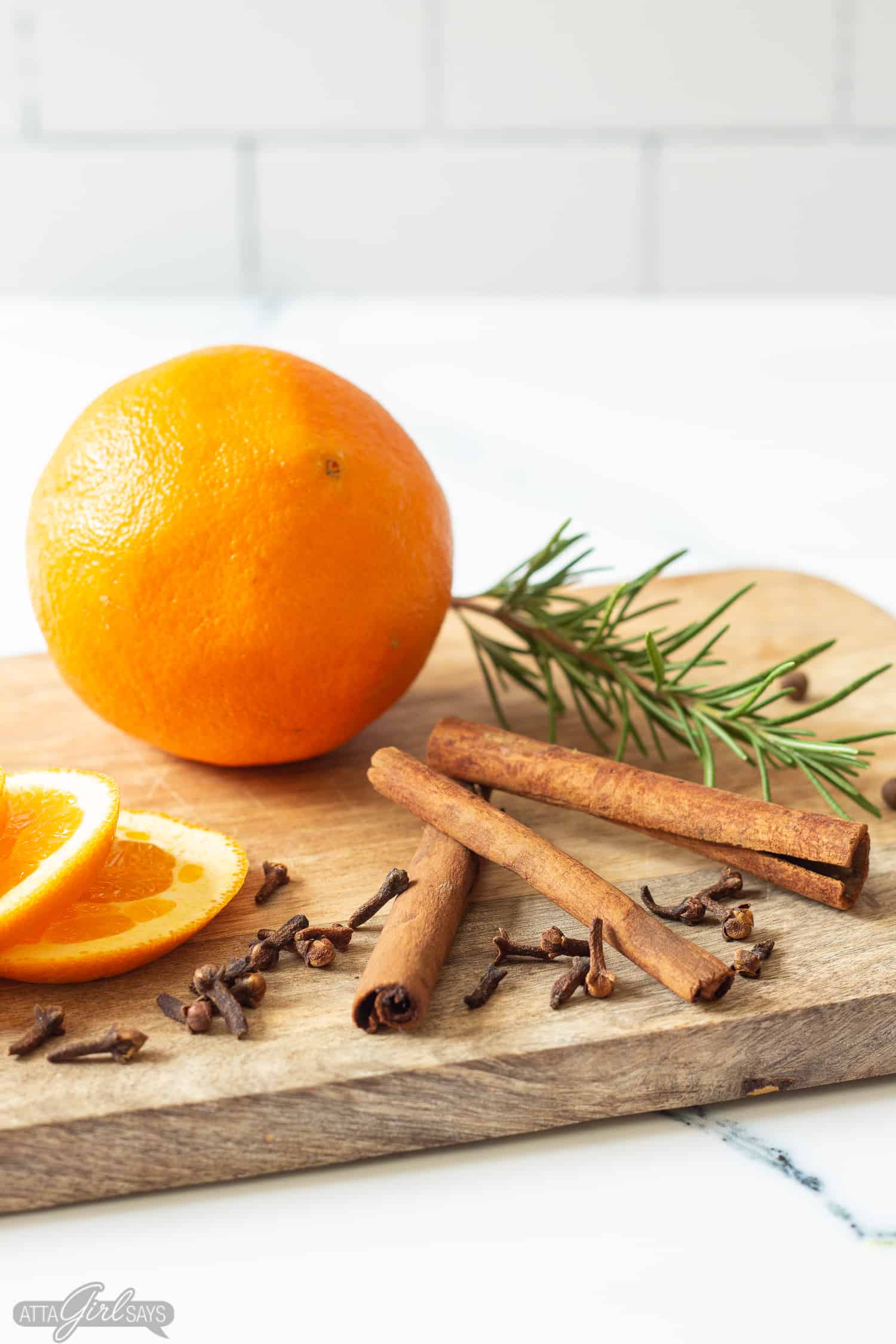 oranges, cinnamon sticks, spices and rosemary on a cutting board