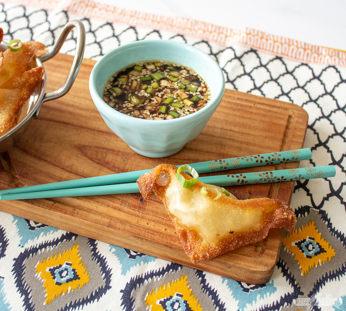 cream cheese wonton with chopsticks and homemade dipping sauce with green onions