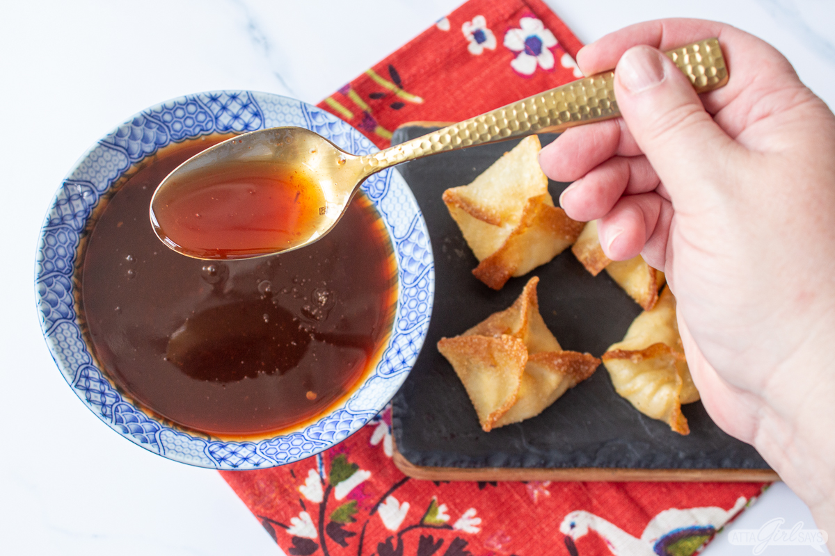 woman holding a spoon over a bowl of homemade sweet and sour sauce