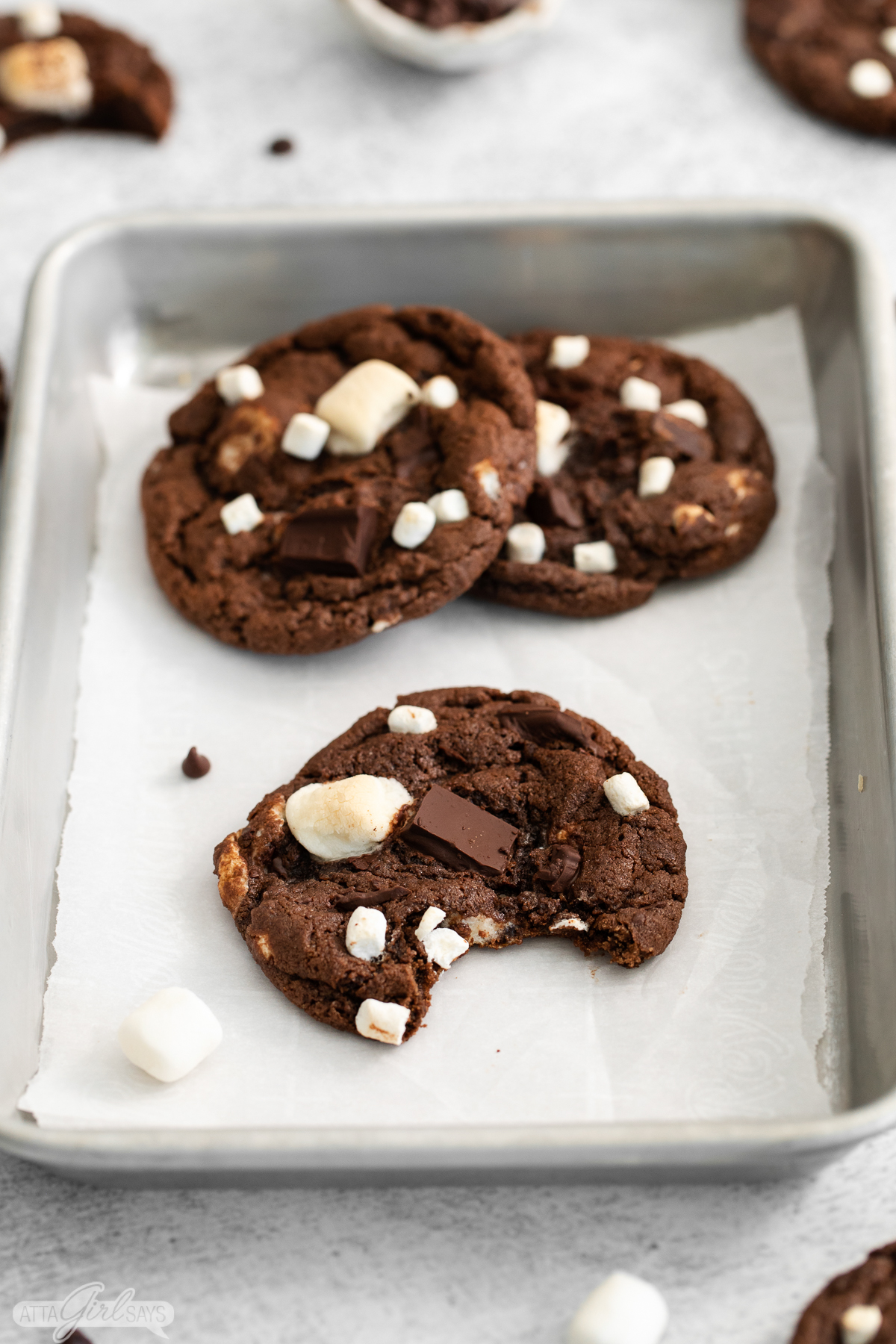 hot cocoa cooke with a bite taken out of it on a pan with other cookies