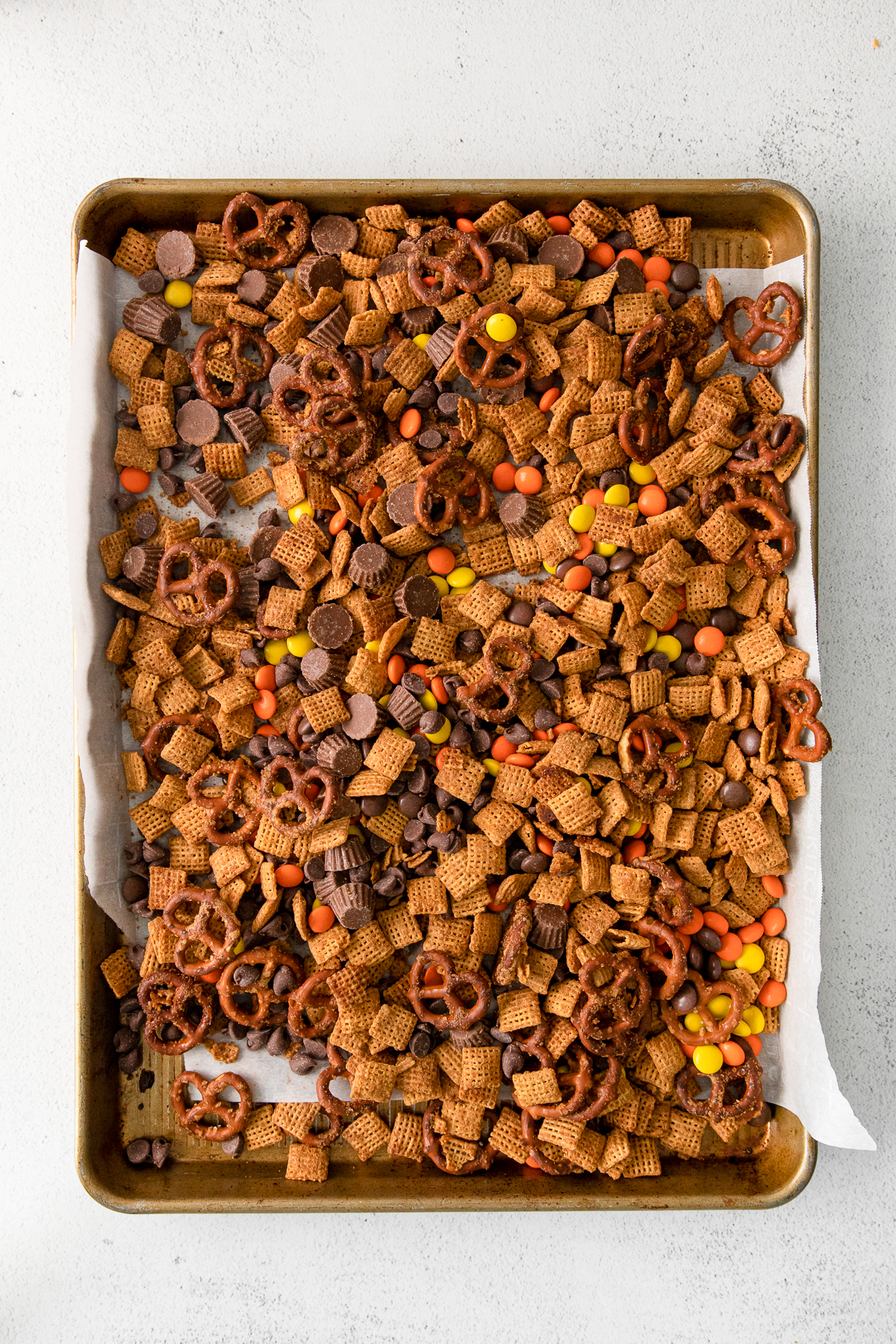 sweet Chex mix recipe with Reese's cups, Reese's pieces on a baking pan