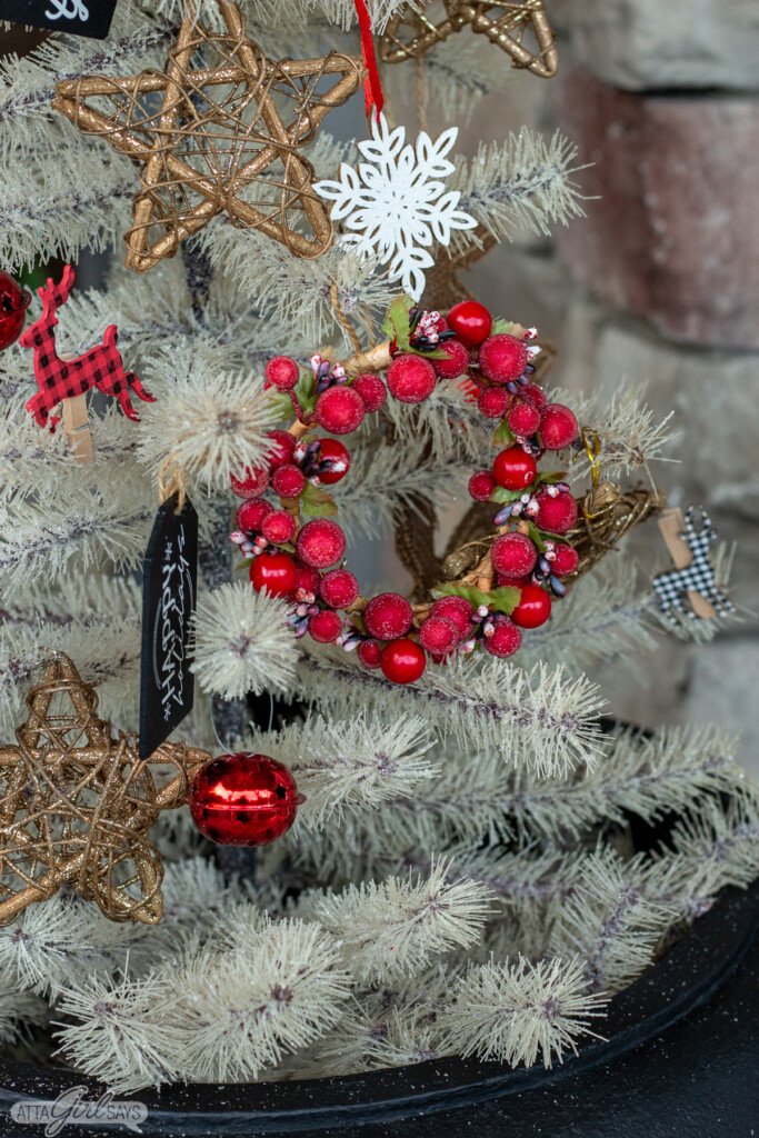 white Christmas tree decorated with glittery stars, bells, chalkboard tags and other ornaments on a large Christmas front porch