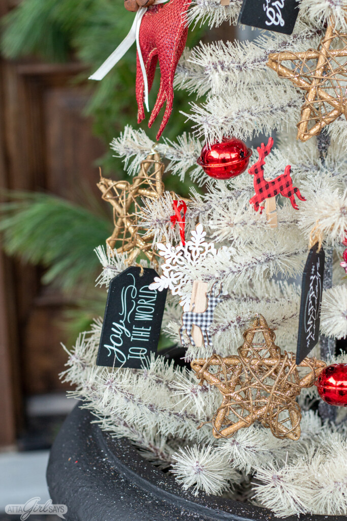 white Christmas tree decorated with glittery stars, bells, chalkboard tags and other ornaments on a large Christmas front porch