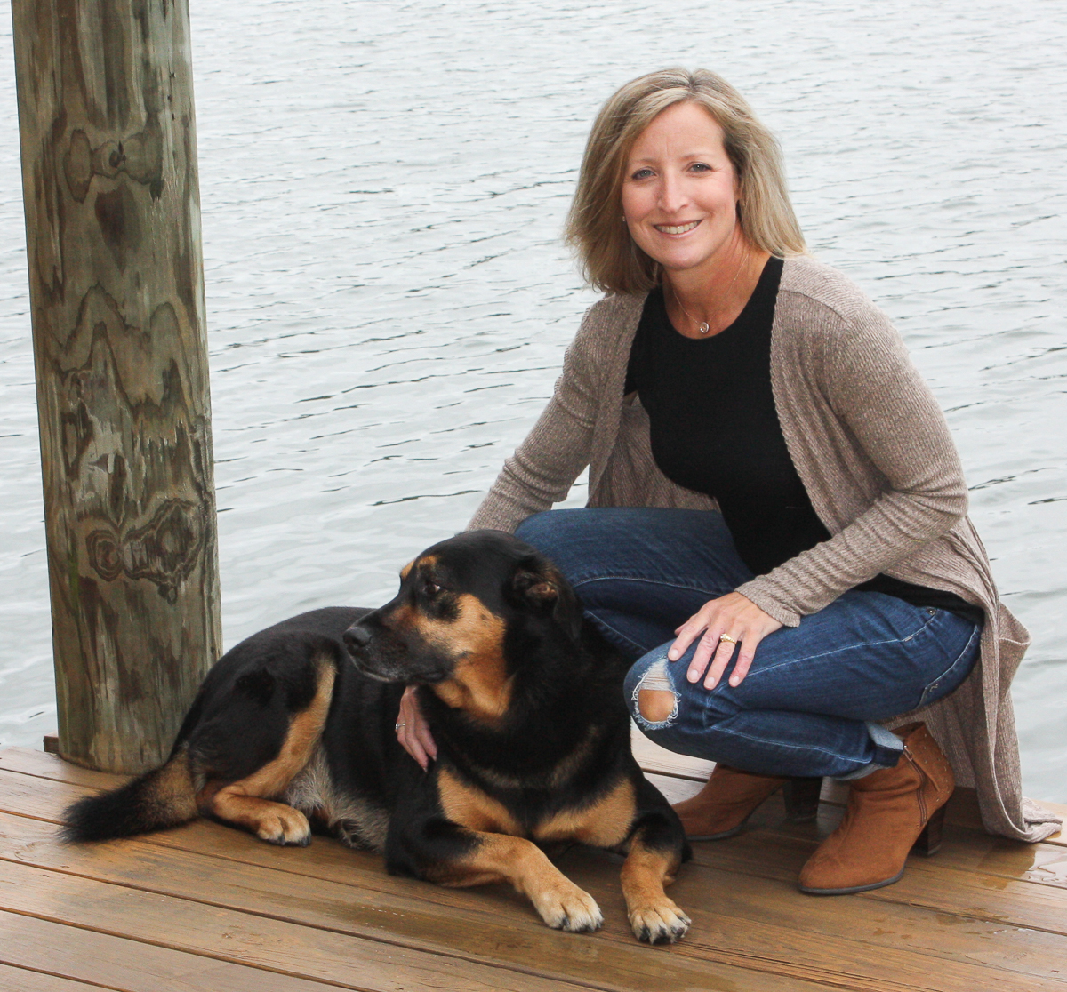 blonde woman with her dog on a lake dock