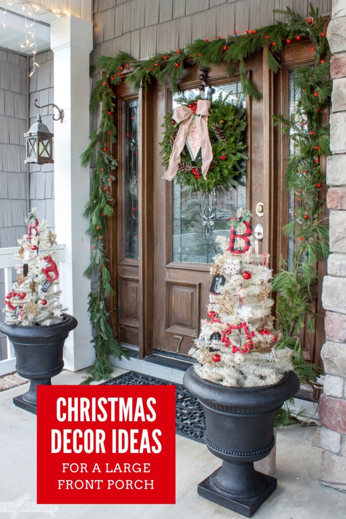 white trees in urns flanking a front door with a garland and wreath for Christmas
