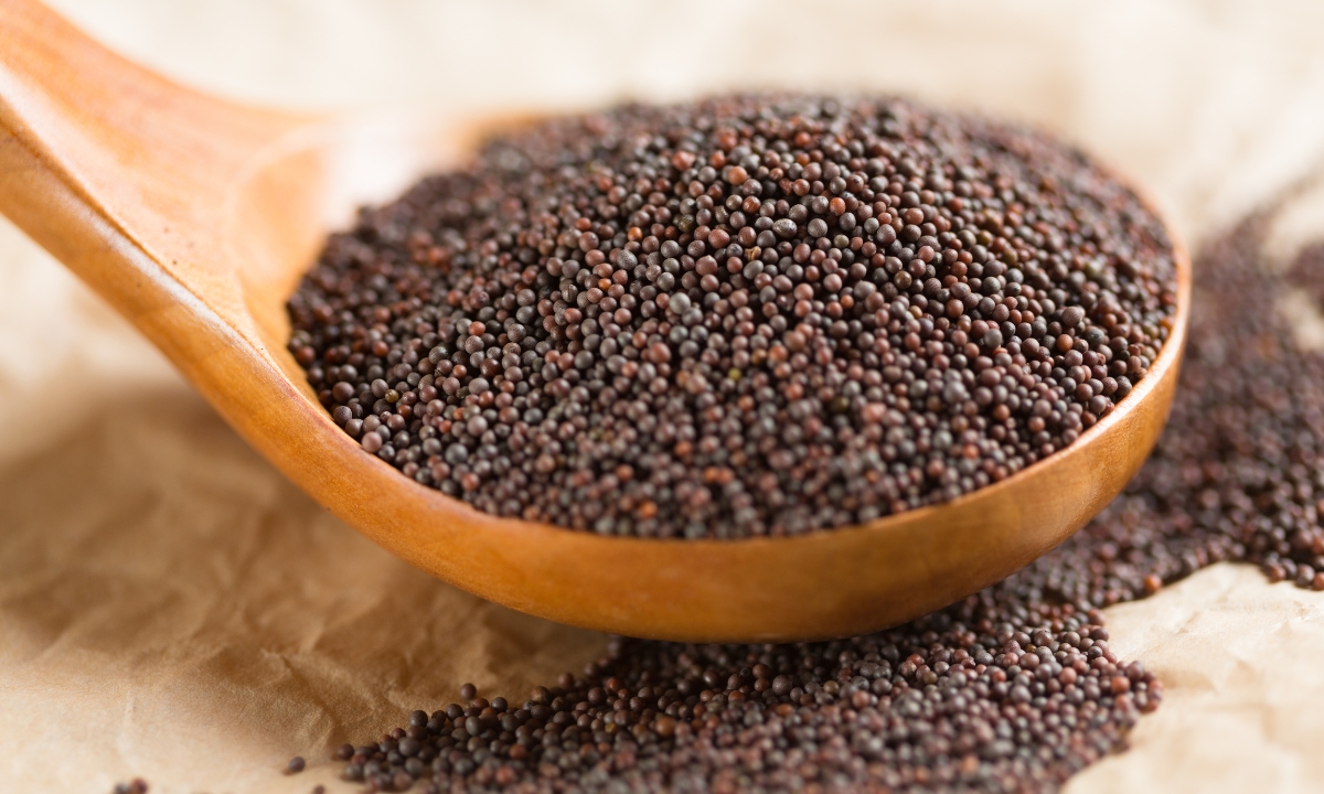 brown mustard seeds in a wooden spoon