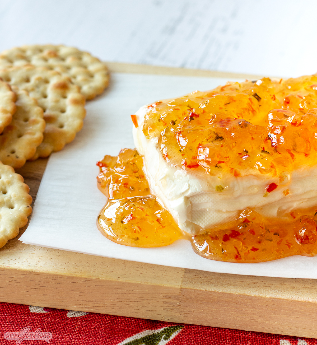 block of cream cheese covered with pepper jelly served with crackers