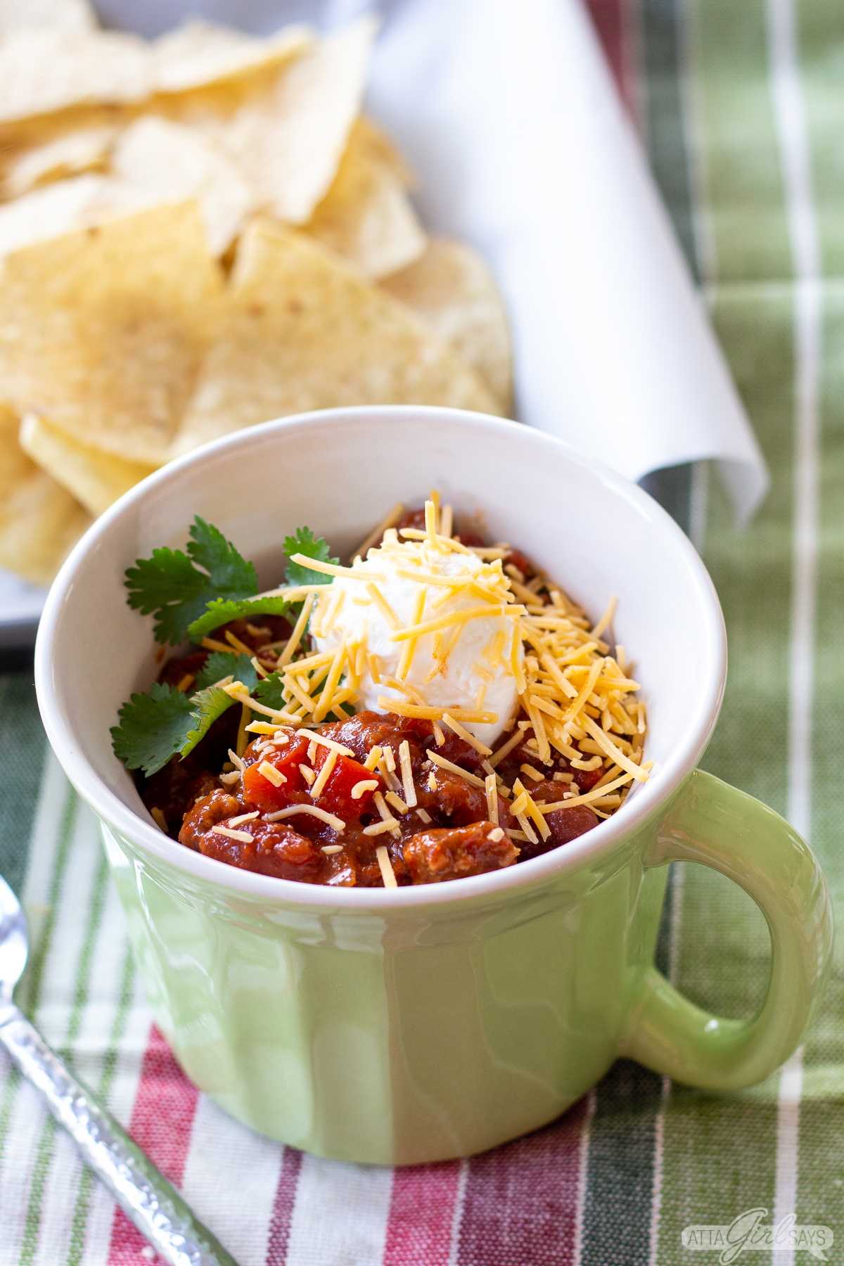 beef and sausage southern chili in a bowl with sour cream, shredded cheese and tortilla chips