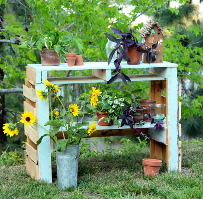 green pallet potting bench with flowers and potted plants