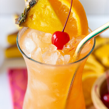 hurricane cocktail in a glass with orange slice, pineapple slice and cherry