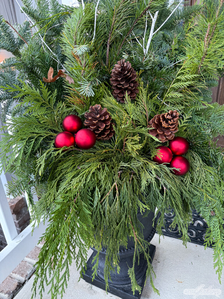 evergreen planter with pinecones and red Christmas balls