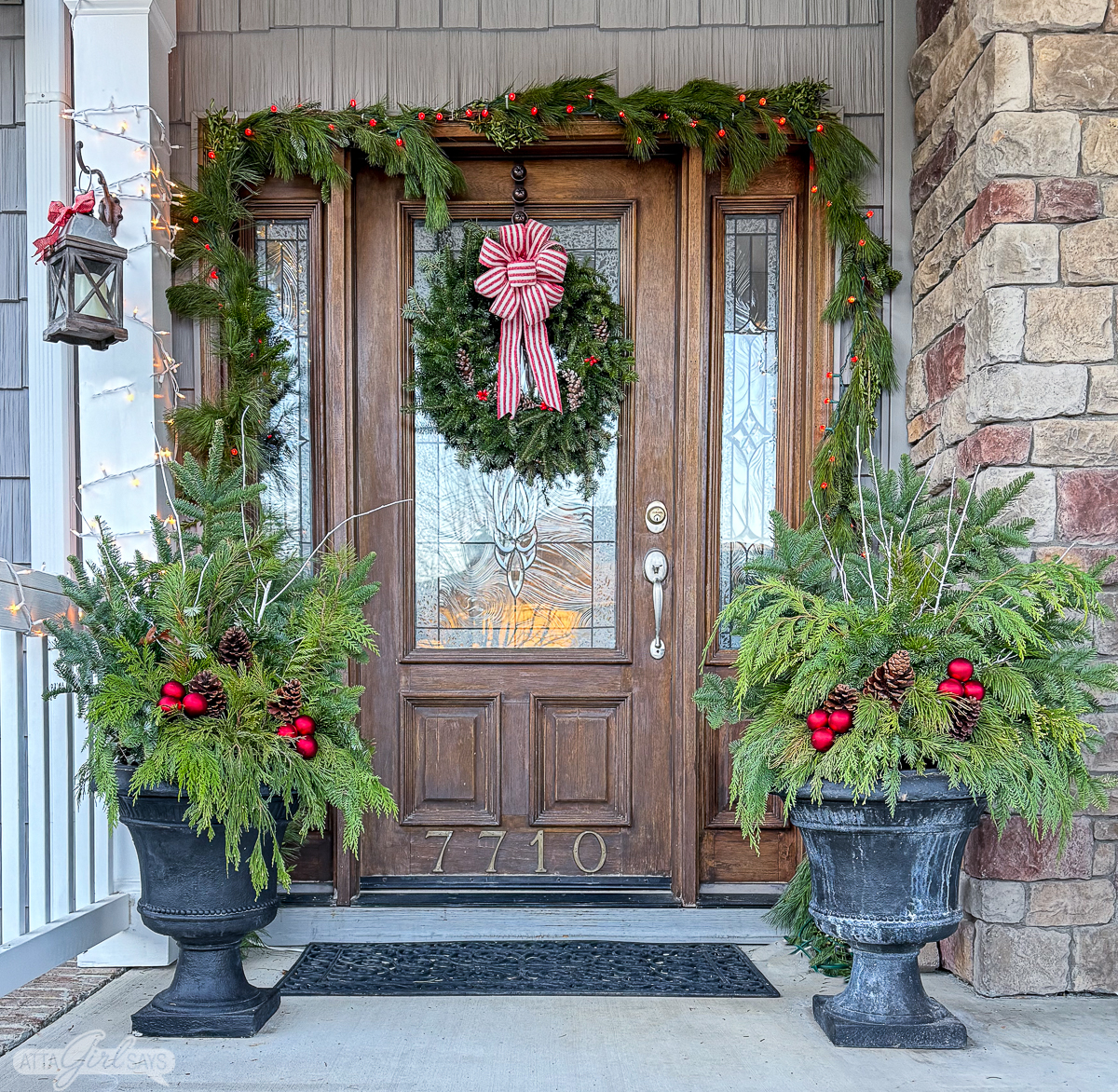 front door with Christmas wreath, garland and urns with greenery