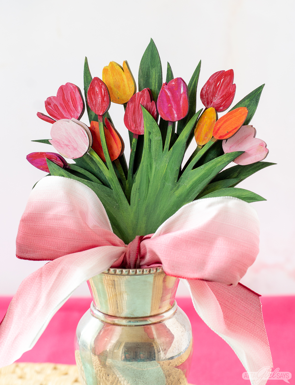 bouquet of painted wood tulips tied with a pink bow in a silver vase