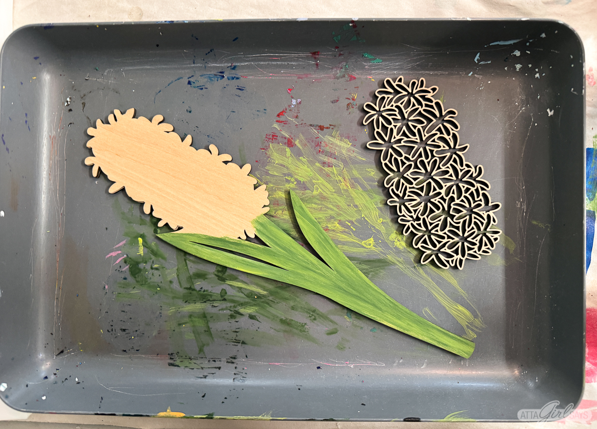 partially painted wooden hyacinth flower laser cut on a paint-splattered gray tray
