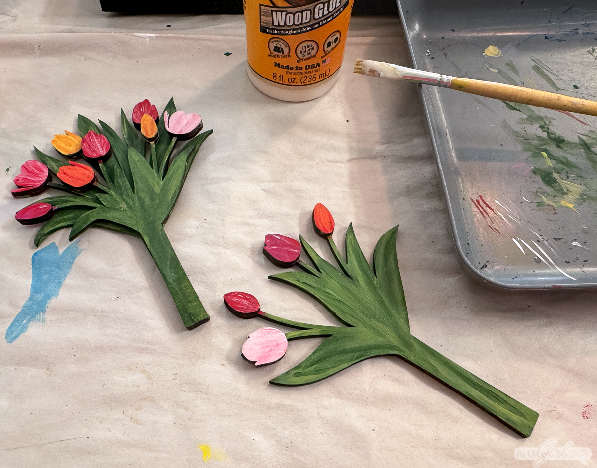 painted wooden tulip bouquet with a paintbrush and wood glue on a work table