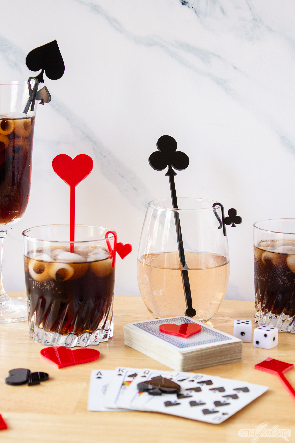 playing card suit swizzle sticks and drink markers in cocktail glasses with a deck of cards for casino night