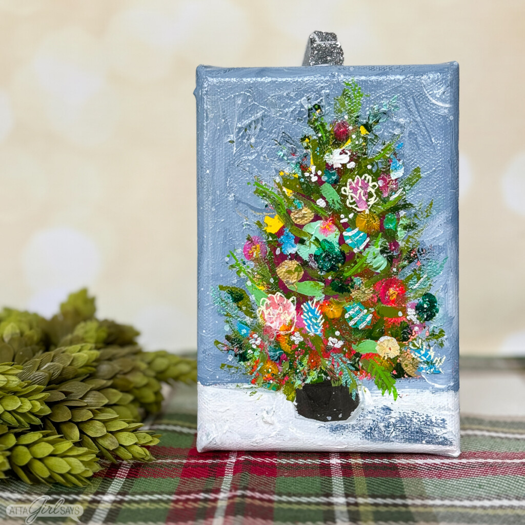 painting of a Christmas tree on a small blue canvas