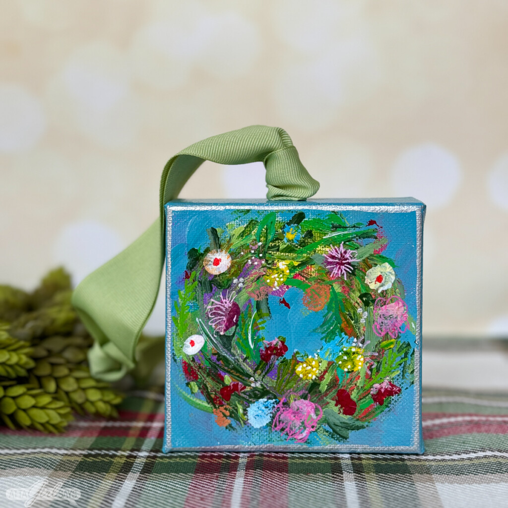 small painting of a Christmas wreath on a blue background