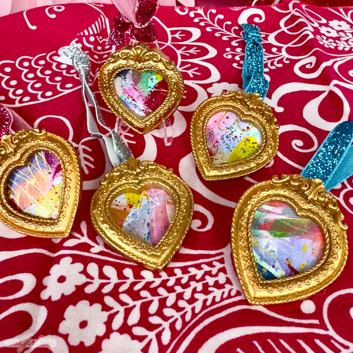 mini heart paintings framed in gold on a pink floral cloth